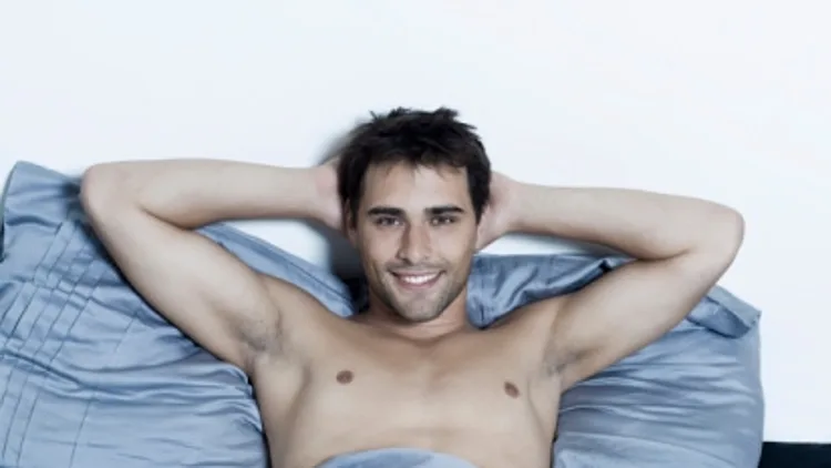 גבר שוכב במיטה ומחייך