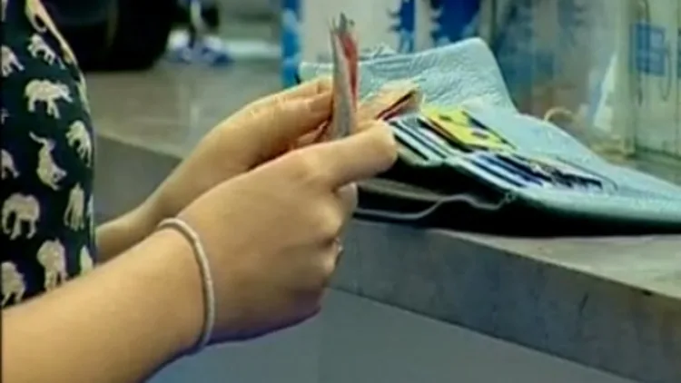 אישה מחזיקה כסף בדלפק בבנק