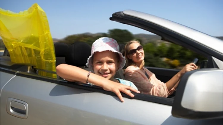 ילדה ואמא נוסעות במכונית פתוחה