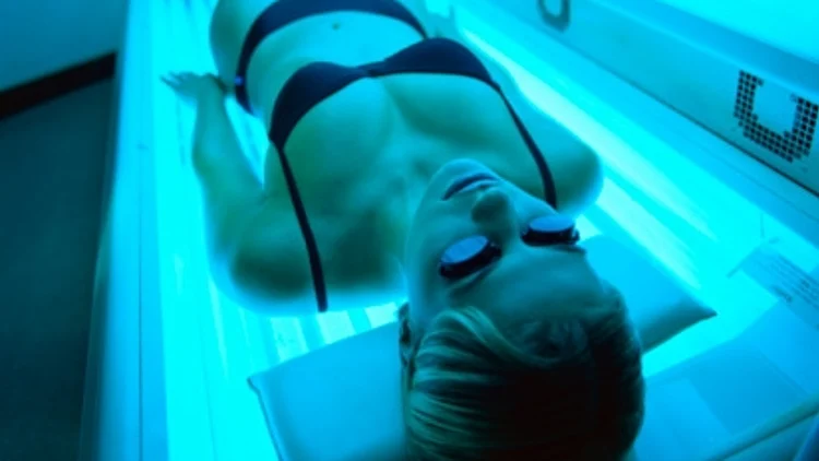 אישה בבגד ים משתזפת על מיטת שיזוף