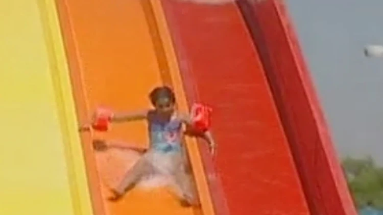 ילדה גולשת במגלשה בעת בילוי משפחתי בפארק שעשועים