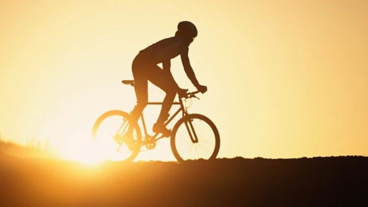 גבר רוכב על אופניים וברקע השקיעה