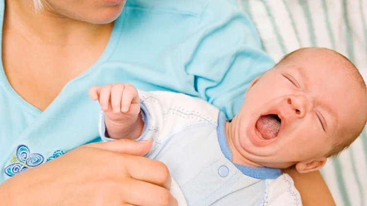 תינוק מפהק בזרועות האמא