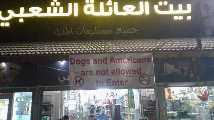 שלט "אין כניסה לכלבים ולאמריקנים" בכניסה לחנות במחנה פליטים בירחו