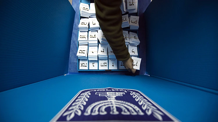 חייל צה"ל מסדר את פתקי ההצבעה באחת הקלפיות