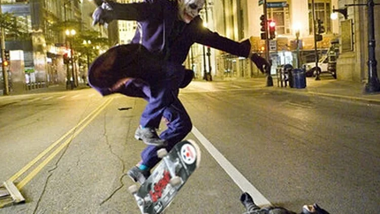 הג'וקר קופץ מעל באטמן עם סקייטבורד