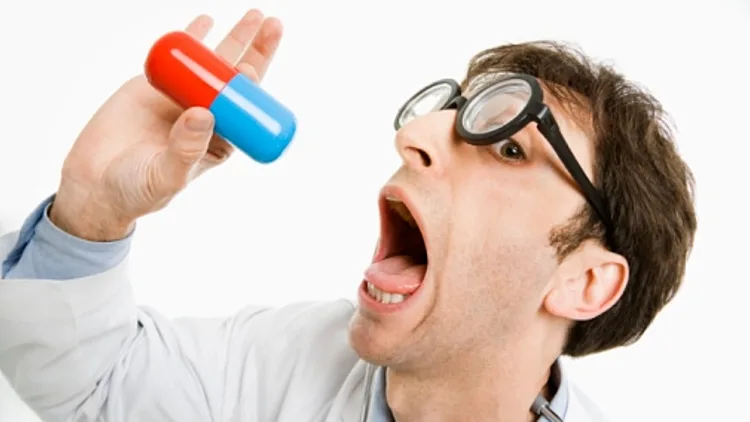 רופא מחזיק קפסולה גדולה בפה פעור