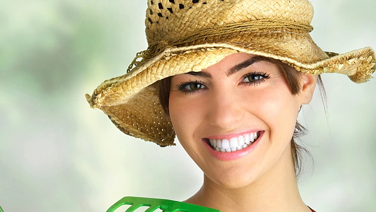 אשה מחזיקה פרחים וכלי גינון