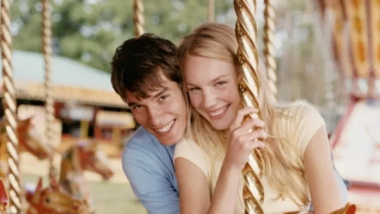 נער ונערה רוכבים על קרוסלה בגן שעשועים