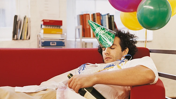 בחור שיכור מרוח על הספה עם כובע יום הולדת