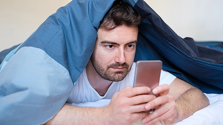 איש במיטה עם טלפון
