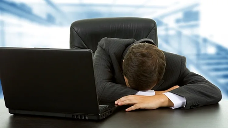 גבר כובש את ראשו בידיו מול מחשב נייד - אילוסטרציה