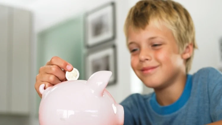 ילד מכניס מטבעות לקופת חיסכון