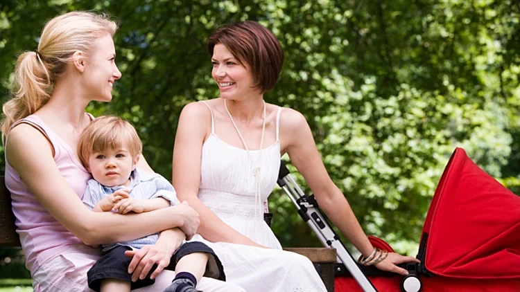 שתי אמהות יושבות באפרק עם הילדים שלהן