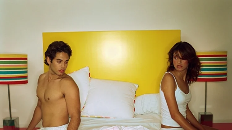 זוג יושב על מיטה, מרוחק אחד מהשני