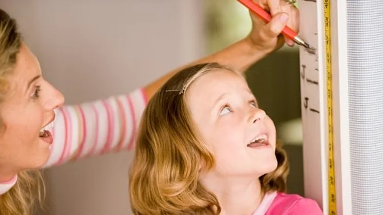 אמא מודדת לילדה את הגובה