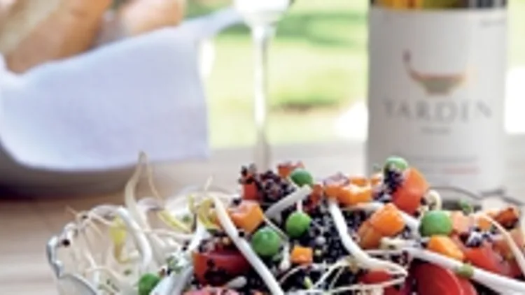 קינואה שחורה עם ירקות - נבטים, גזר ואפונה מוגשת בצלחת עם יין לבן