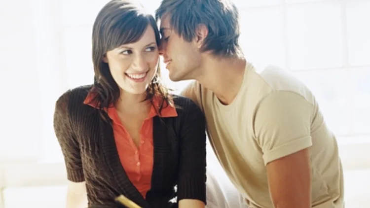 אילוסטרציה. גבר צעיר לוחש על אזנה של אישה צעירה. נראים כמו זוג בחיזור