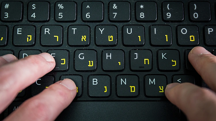 איש מקליד על מקלדת עם אותיות בעברית