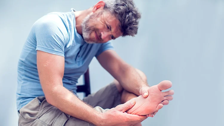 Pain,in,the,foot,,man,holds,hands,to,his,feet,