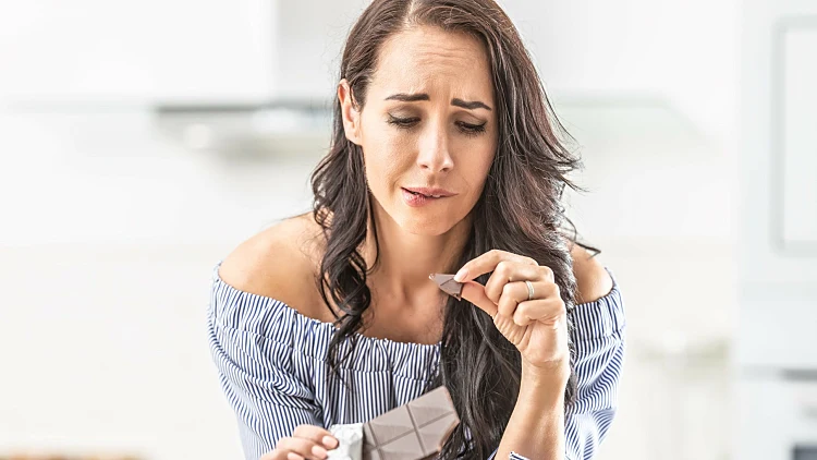 Guilty Expression Of A Woman Who Bites Off From A Chocolate Bar.