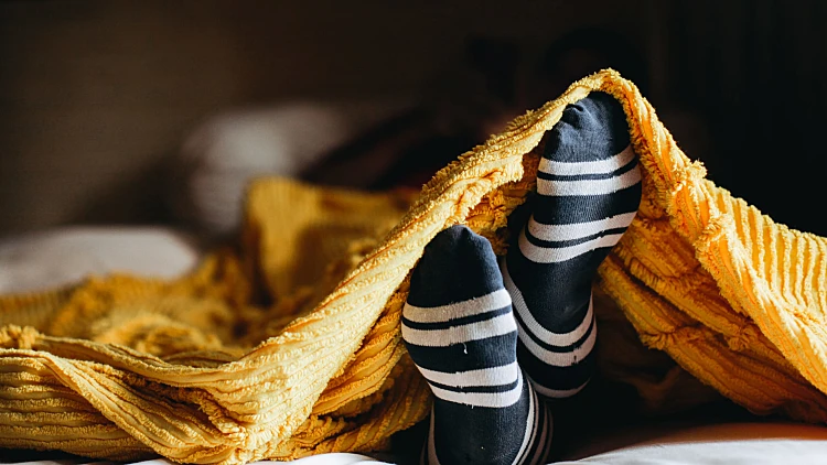 Cozy,position,of,foot,in,warm,socks,under,the,blankets