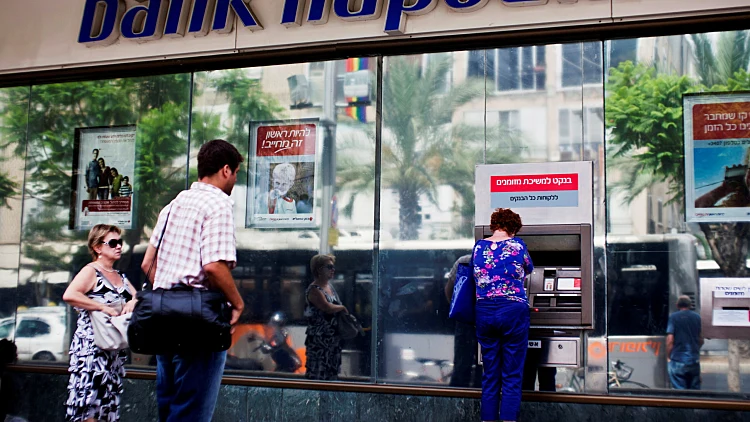 File Photo: A Woman Uses An Automated Teller Machine Outside A Bank Hapoalim Branch In Tel Aviv, Israel