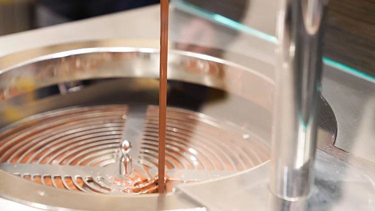 Chocolate,fountain,confectioner,filling,candy,mold,with,chocolate,at,confectionery