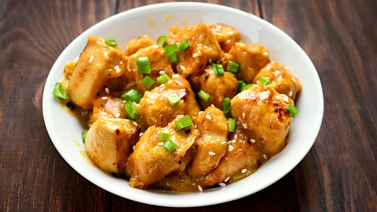 Chicken,with,orange,sauce,in,white,bowl,,close,up,view.