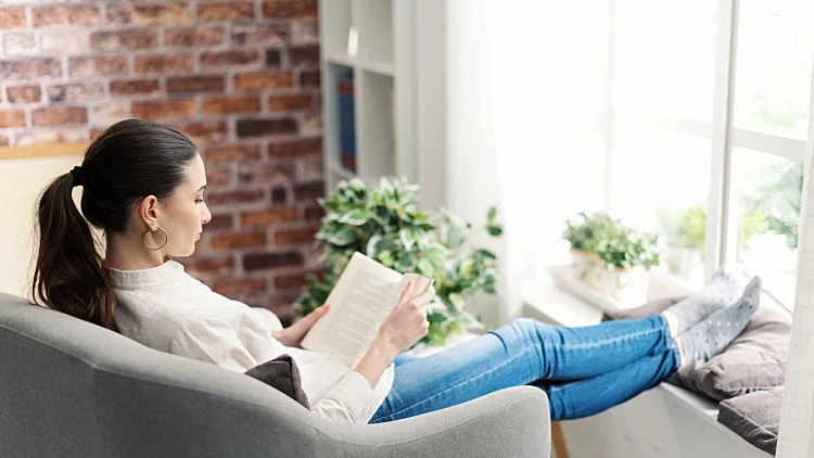 Young,woman,relaxing,at,home,next,to,a,window,,she