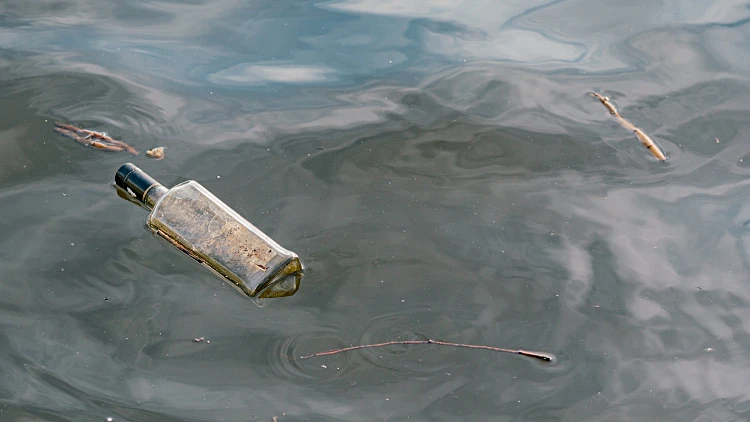 Dirty,glass,empty,bottle,floating,in,water.,pollution.,dangerous.,nature.