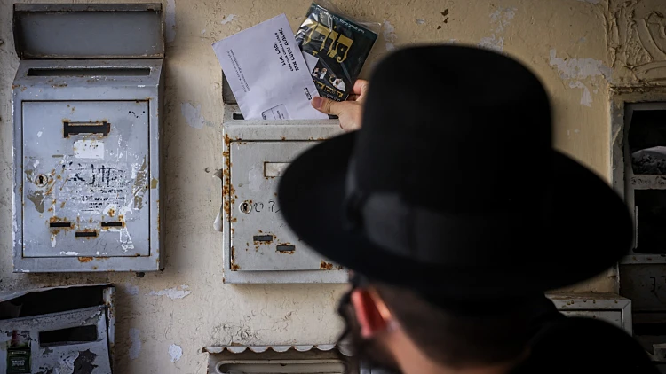 צעיר חרדי אוחז בצו גיוס בשכונת מאה שערים בירושלים