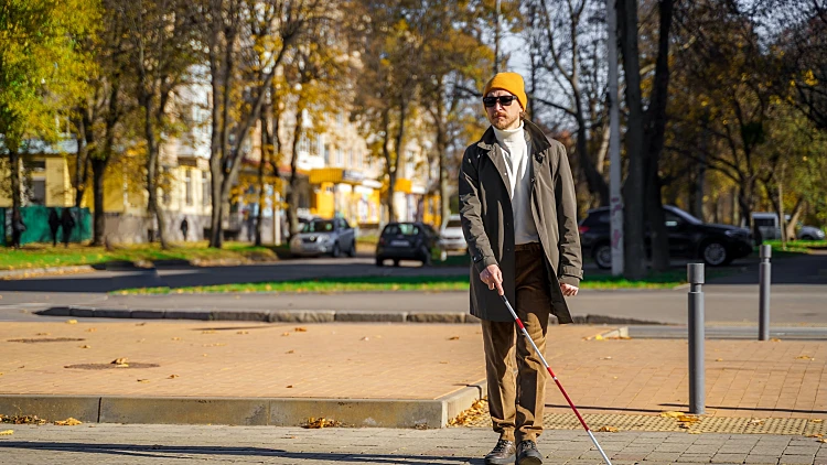 Blind,man,with,a,cane,walks,along,a,pedestrian,crossing