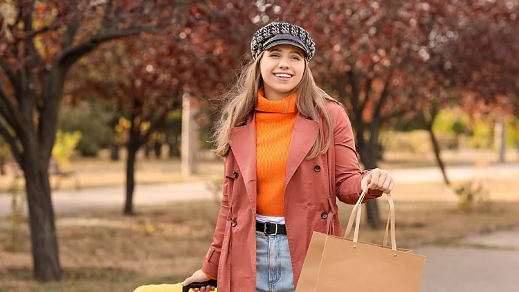 בחורה בפארק עם שלכת עם טרולי ושקית קניות