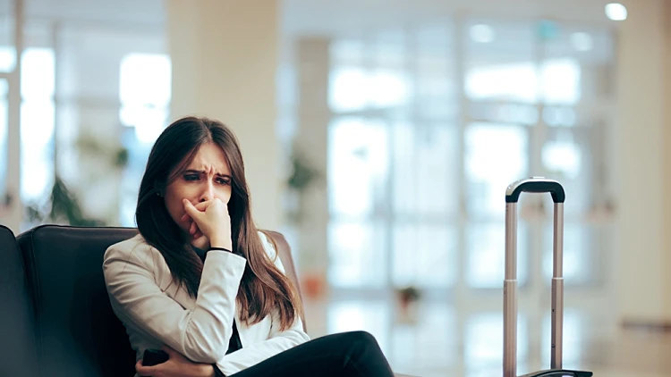 אישה עצובה, חוששת, כועסת לפני טיול או טיסה בחדר עם טרולי