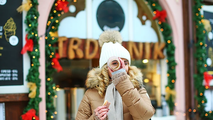 Trdelnik,אישה צ'כית אוכלת טרדלינק בשוק חג המולד בפרא