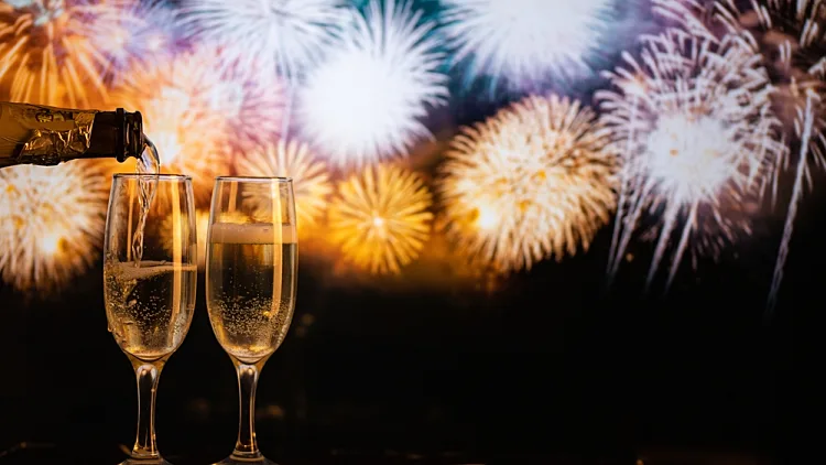 כוסות שמפיניה על רקע זיקוקים לשנה החדשה