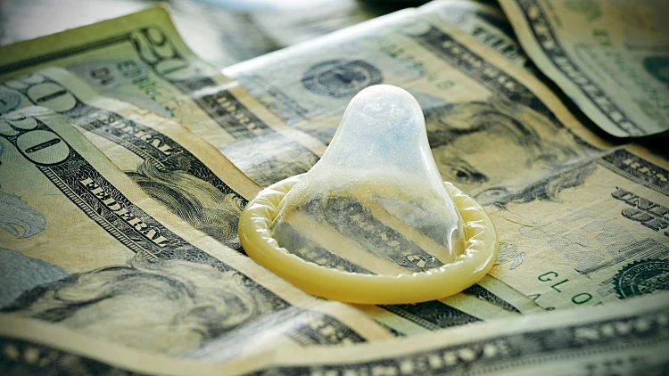A,condom,on,a,pile,of,dollar,banknotes,,depicting,the