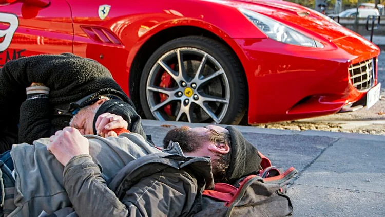 הומלס שוכב לצד רכב יוקרה (אילוסטרציה)