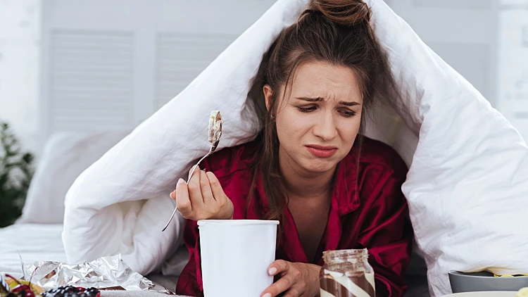 אישה עצובה אוכלת גלידה בהתקף אכילה רגשית