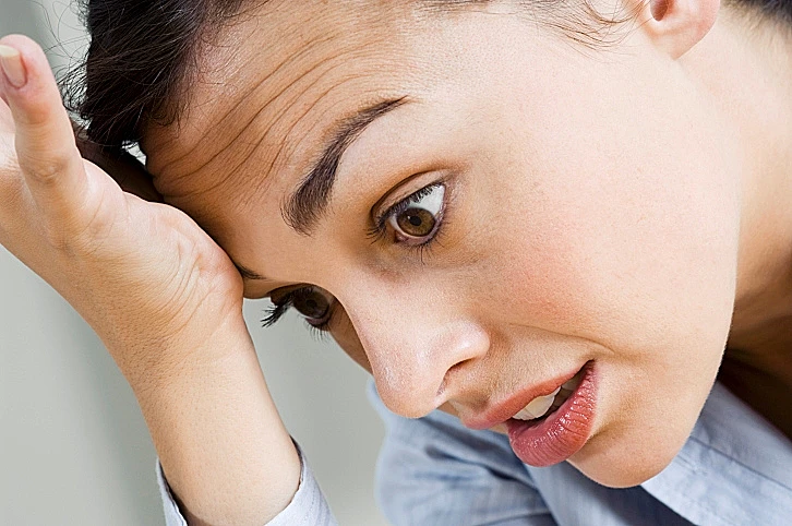 פנים של אישה מתלבטת או לחוצה, יד על המצחו