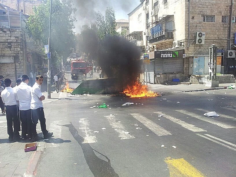 כבאים מכבים פח אשפה שהוצת על ידי חרדים בשכונת מאה שערים
