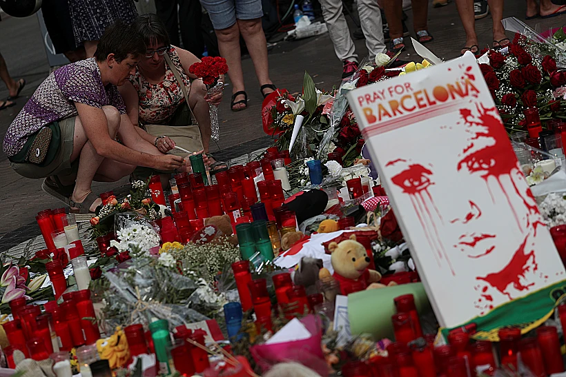 שתי נשים מדליקות נרות לזכר קורבנות הפיגוע בברצלונה שבספרד