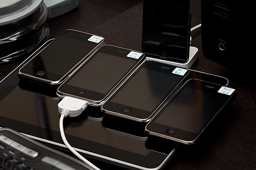 שורת אייפונים עם מערכות הפעלה בגרסאות שונות מונחת על מכשיר אייפד