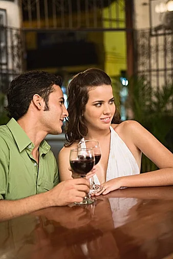 אשה וגבר יושבים צמוד ושותים יין