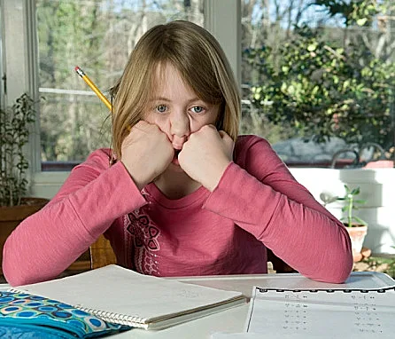 תלמידה מתוסכלת יושבת בשולחן כתיבה