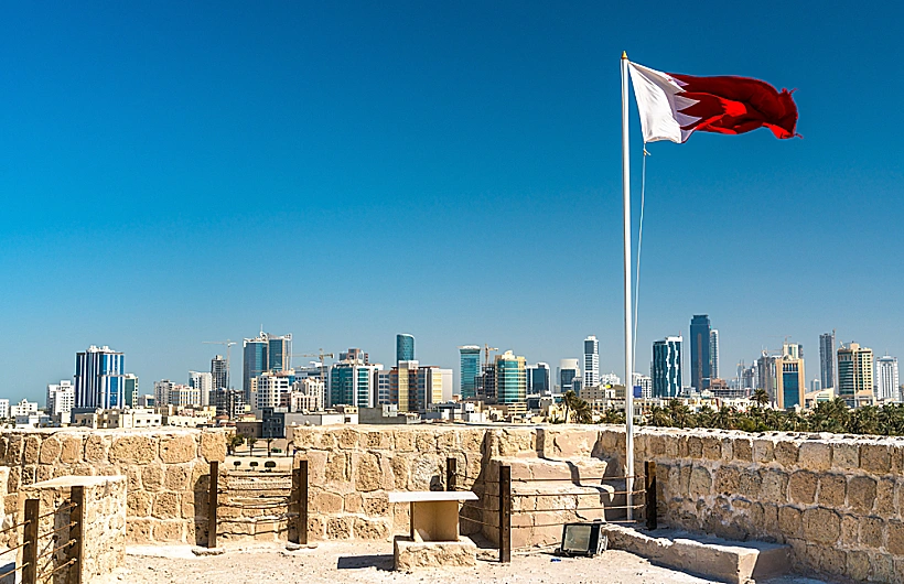 Bahrain,flag,with,skyline,of,manama,at,bahrain,fort.,a