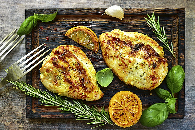 Grilled,spicy,chicken,breast,with,herbs,on,old,cutting,board.food