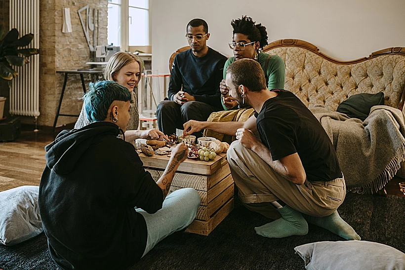 Female And Male Friends Having Breakfast In Living Room At Home
