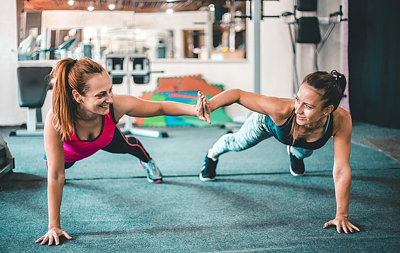 Two,female,friends,exercising,together,in,the,gym